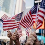 The hands of onlookers waving flags at a Labor Day parade are featured in this image.