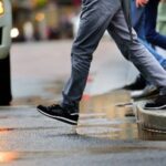 Walkers are pictured here stepping off the curb as the light changes on a dreary day.