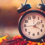 A clock sits on a dresser here with colorful leaves serving as a reminder that we 