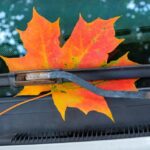 A colorful Maple leaf is tucked under a windshield wiper in this iconic fall scene.