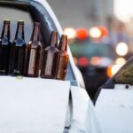 Beer bottles are lined up in a row here on the back of a pickup truck involved in a crash.